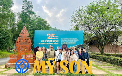 Group at My Son Sanctuary entrance, Vietnam, with temple replica and anniversary sign.