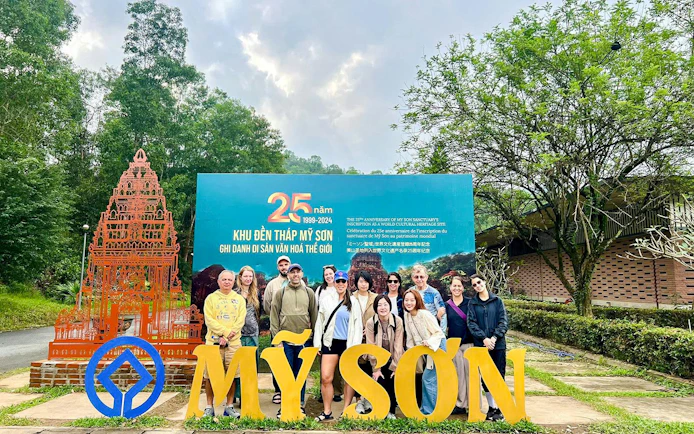 Group at My Son Sanctuary entrance, Vietnam, with temple replica and anniversary sign.