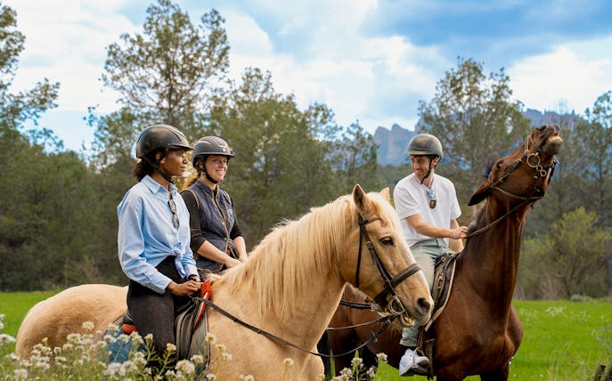 Tourists on horseback with a guide in Montserrat, surrounded by lush greenery.