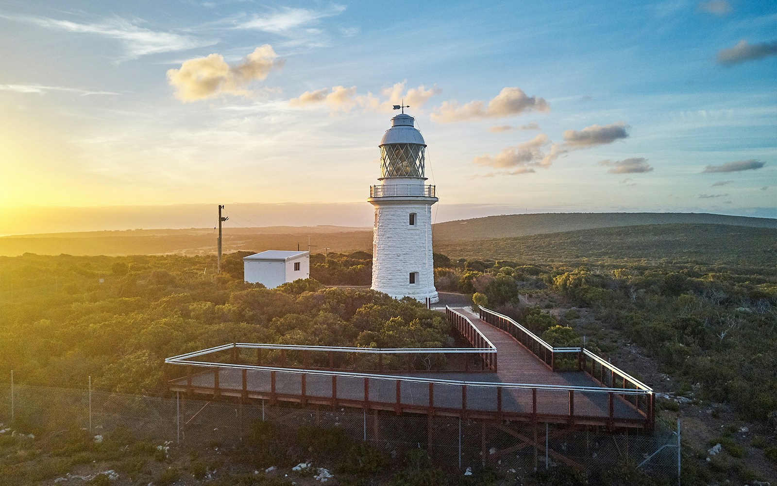 Cape Naturaliste Lighthouse at sunset with boardwalk and coastal vegetation, Western Australia.
