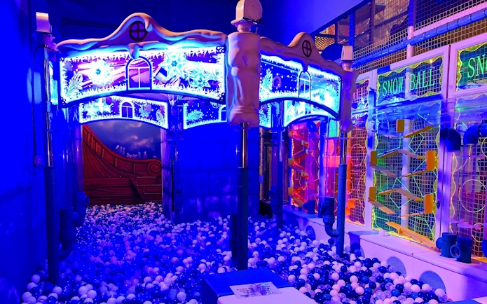 Indoor playground with colorful ball pit and illuminated play structures at Amazonia Singapore.