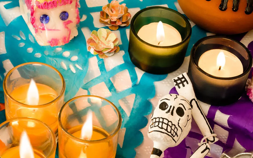 Candles and sugar skulls on colorful papel picado at Mixquic Day of the Dead celebration.