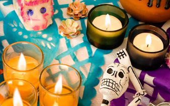 Candles and sugar skulls on colorful papel picado at Mixquic Day of the Dead celebration.