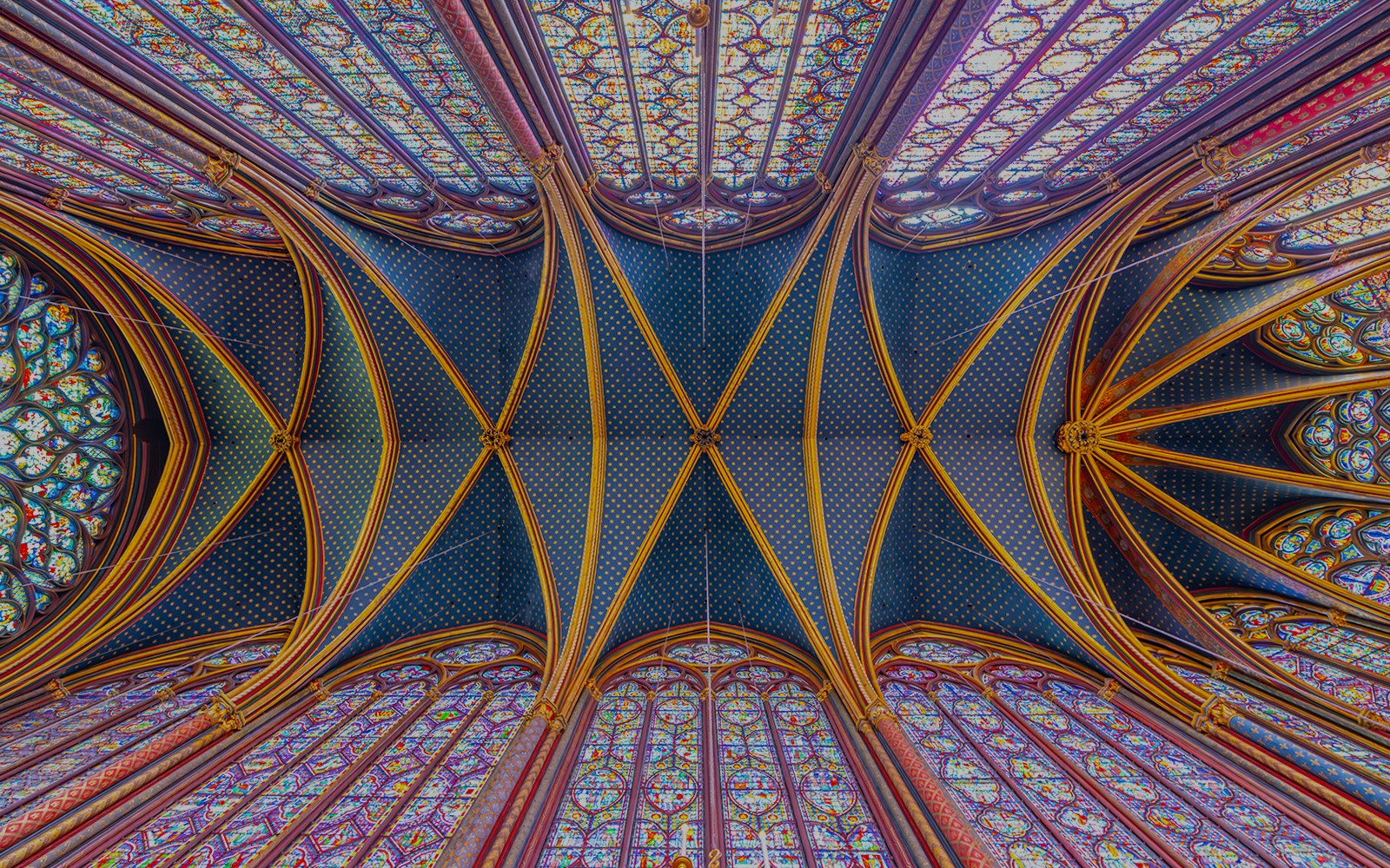 Monumental interior vaulted ceiling of Upper Chapel of Sainte-Chapelle with stained glass windows.
