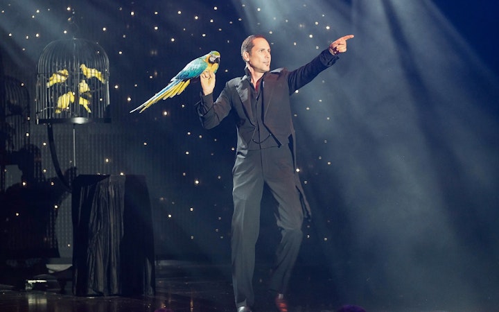 Performer with parrot on stage at V - The Ultimate Variety Show.