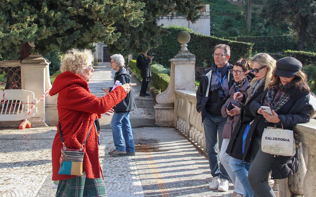 Tour guide explaining to visitors at Tivoli Villa d'Este gardens.