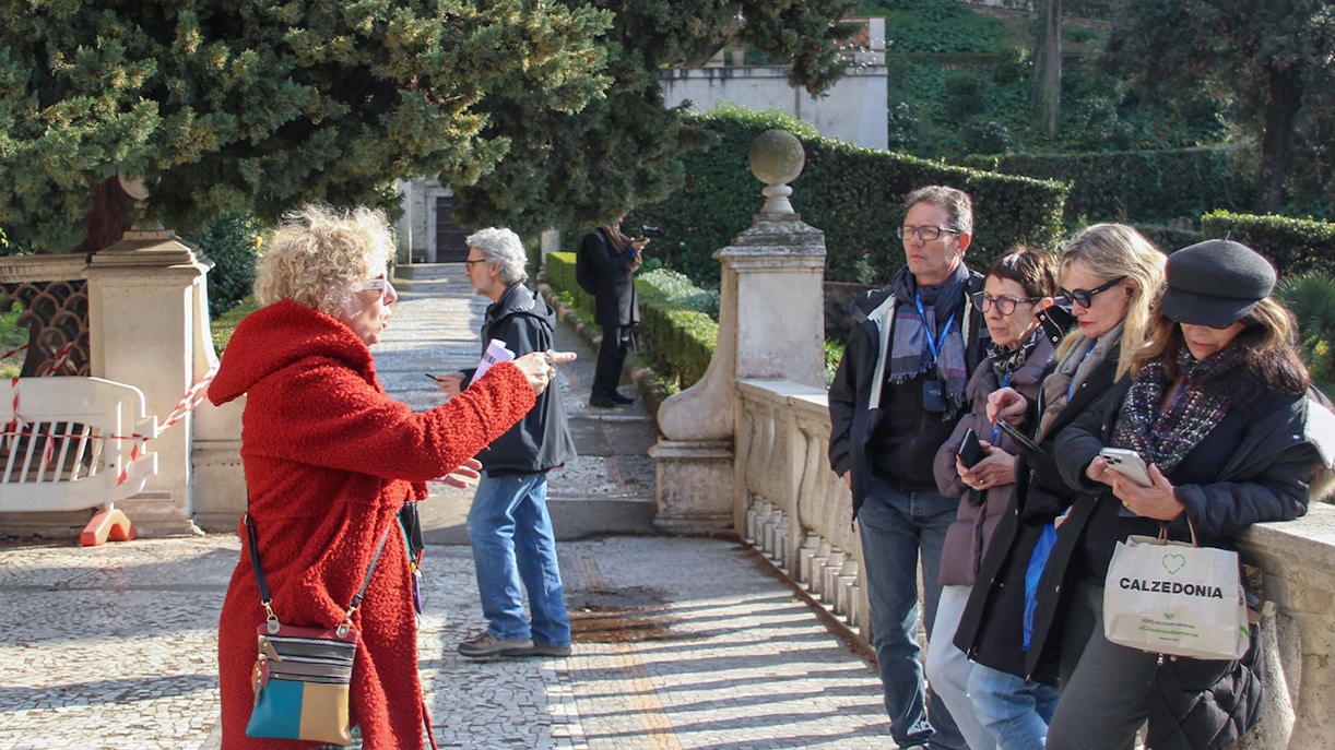 Tour guide leading visitors through Tivoli Villa d'Este gardens in Italy.