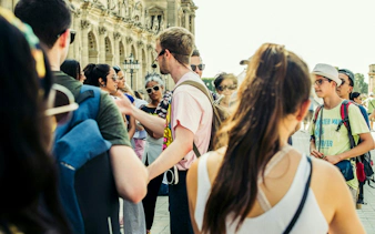 Tourists listening to a city guide near a historic building.