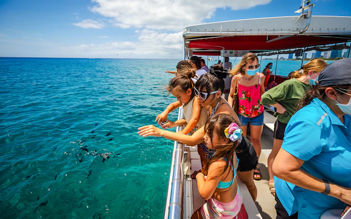 Guests observing fish from a Hawaii glass-bottom boat.
