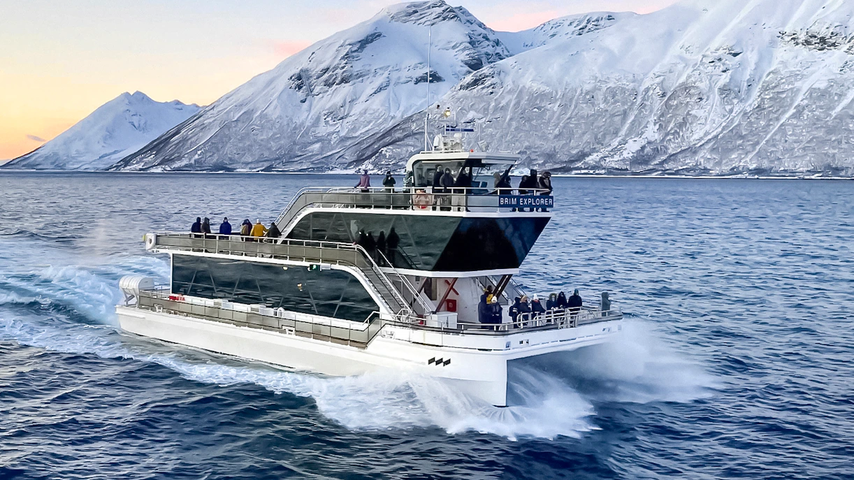Cruise ship on Arctic fjord near Tromso with snowy mountains in background.