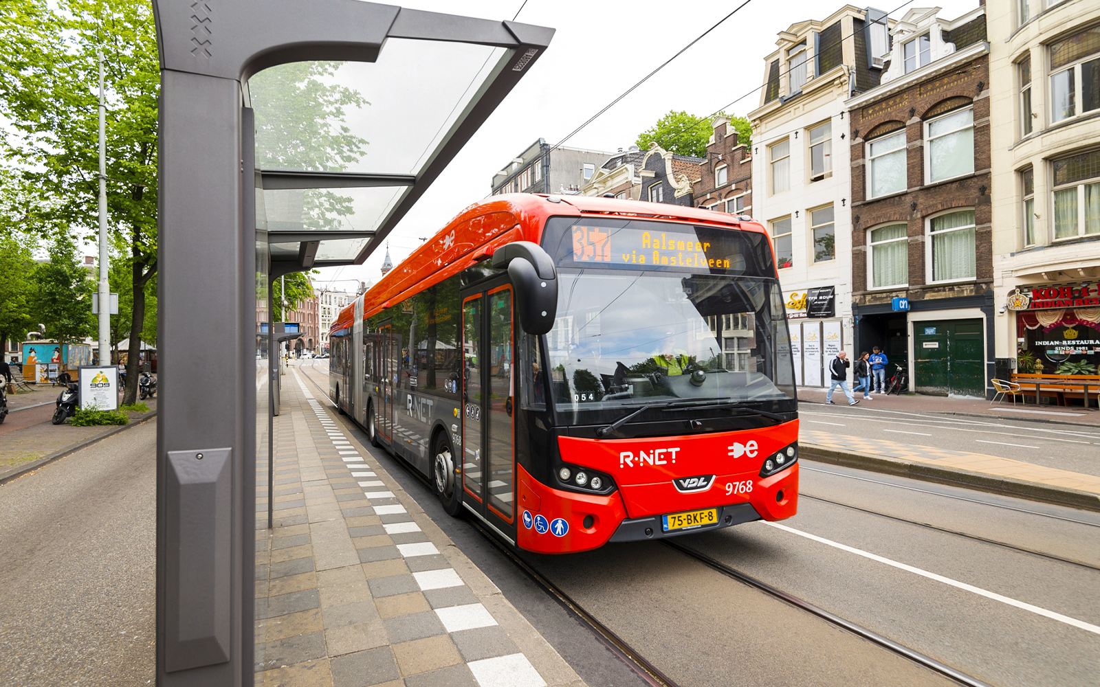 Amsterdam Airport Express bus at a city stop with passengers boarding.