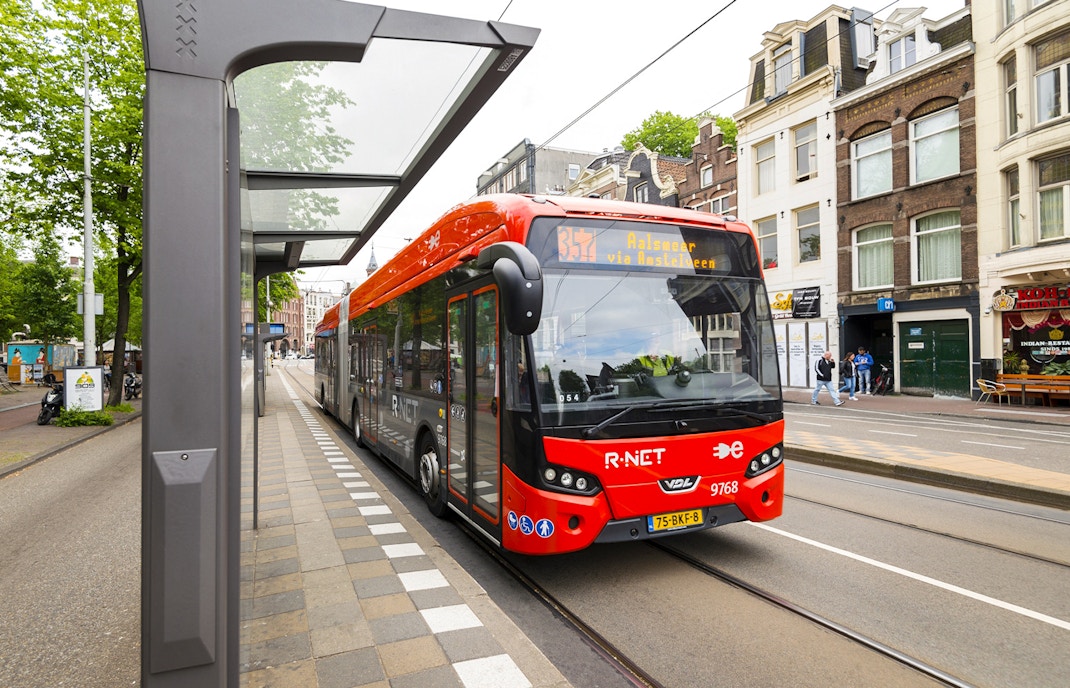 Amsterdam Airport Express bus at a city stop with passengers boarding.