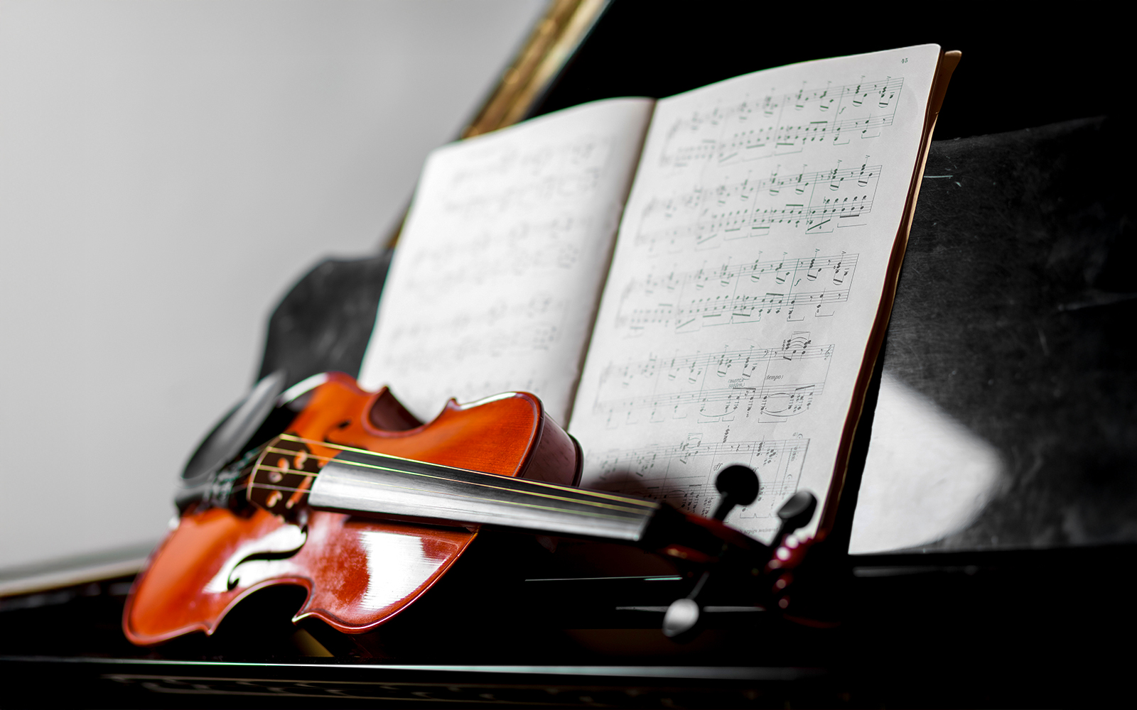 Violino apoiado em um piano de cauda, simbolizando um ambiente de música clássica.