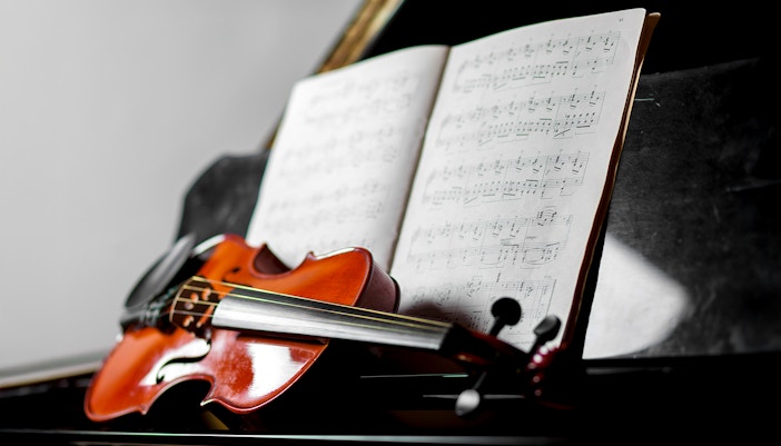 Violino apoiado em um piano de cauda, simbolizando um ambiente de música clássica.