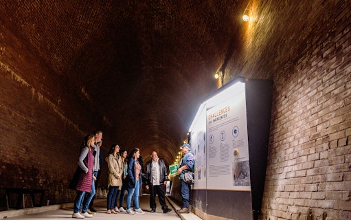 Guide explaining information to tourists in the Tailrace Tunnel.