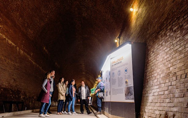 Guide explaining information to tourists in the Tailrace Tunnel.