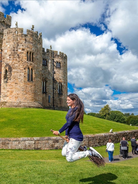Woman practicing broomstick flying at Alnwick Castle, England.