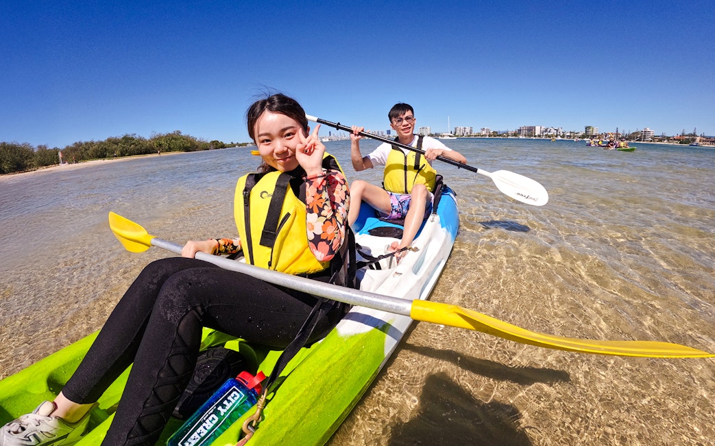Kayakers paddling in Broadwater, Gold Coast with city skyline in background.