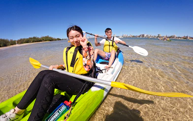 Kayakers paddling in Broadwater, Gold Coast with city skyline in background.