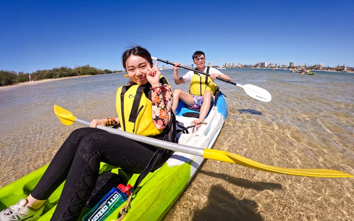 Kayakers paddling in Broadwater, Gold Coast with city skyline in background.