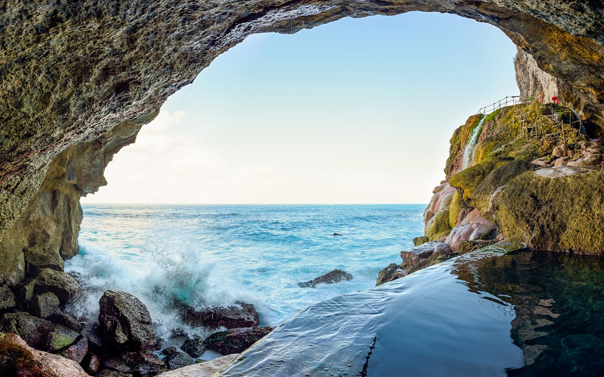 Coastal cave view with ocean waves and rocky cliffs, Nusa Penida Island tour.