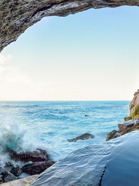 Coastal cave view with ocean waves and rocky cliffs, Nusa Penida Island tour.
