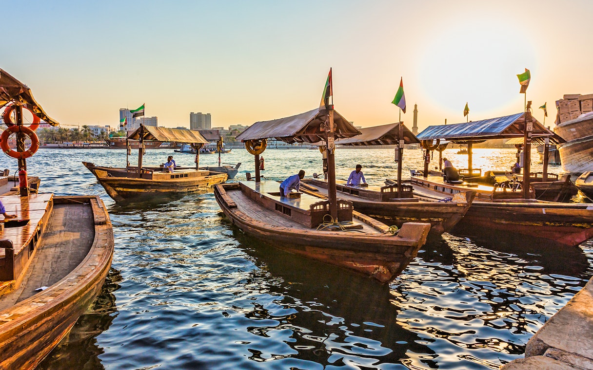 Traditional wooden abras on Dubai Creek at sunset.
