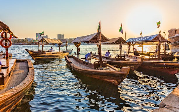 Traditional wooden abras on Dubai Creek at sunset.