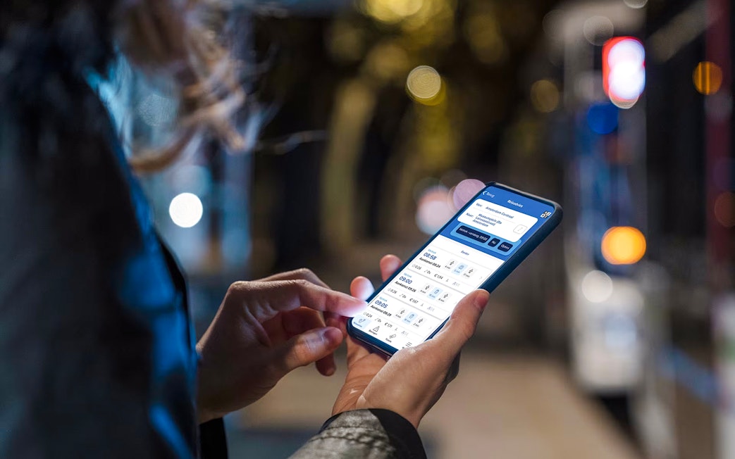 Person using Amsterdam GVB Public Transport app on smartphone at night.