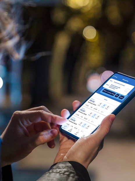 Person using Amsterdam GVB Public Transport app on smartphone at night.