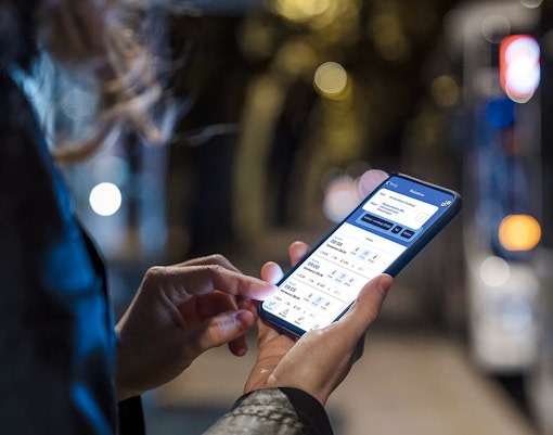 Person using Amsterdam GVB Public Transport app on smartphone at night.