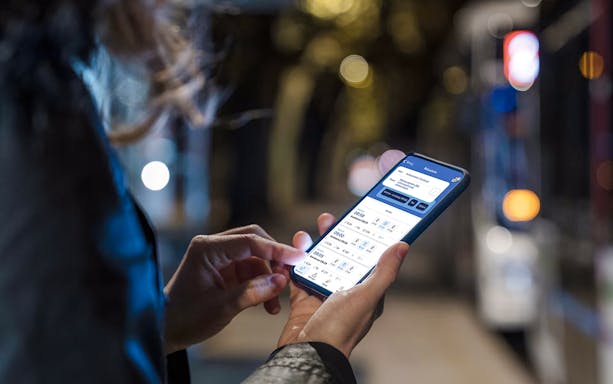 Person using Amsterdam GVB Public Transport app on smartphone at night.
