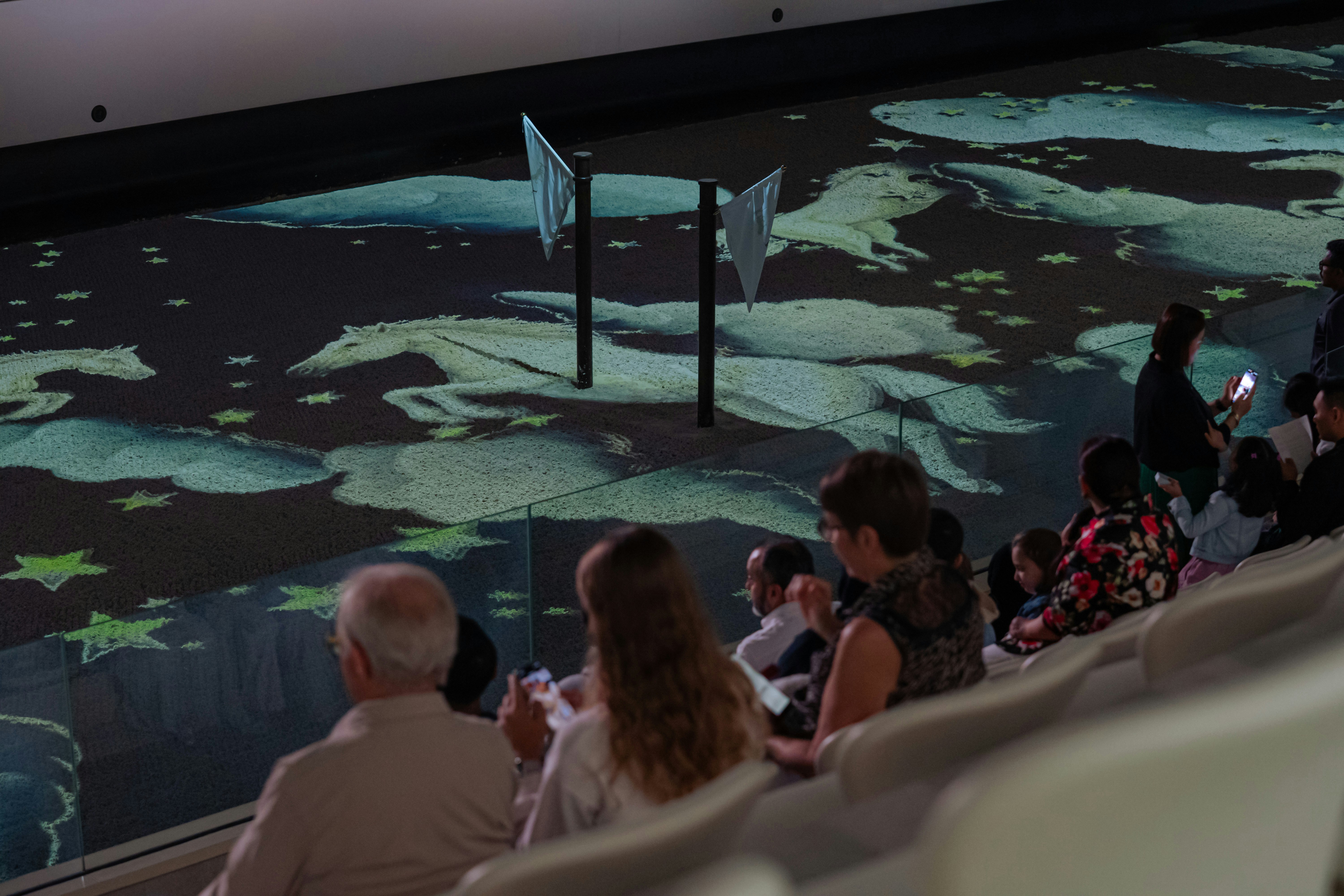Audience watching horse projections at Abu Dhabi Royal Equestrian Arts show.