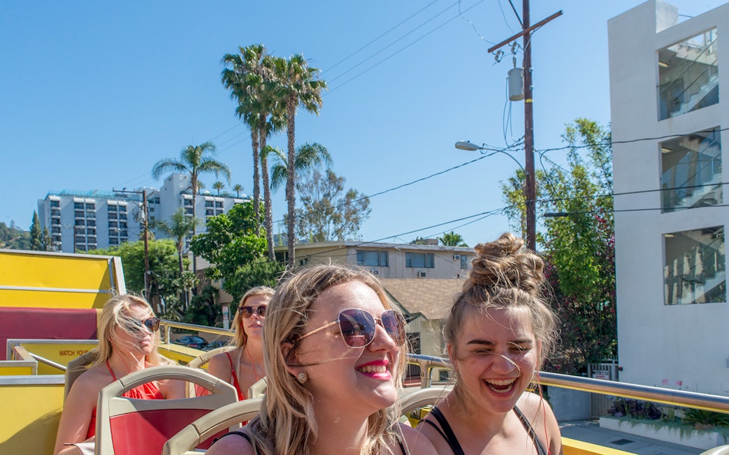 Tourists enjoying a Los Angeles hop-on hop-off bus tour with cityscape views.