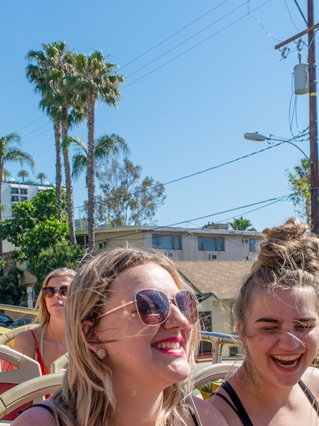 Tourists enjoying a Los Angeles hop-on hop-off bus tour with cityscape views.