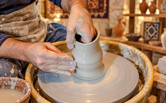 Local artisan shaping clay on a pottery wheel in Baku workshop.