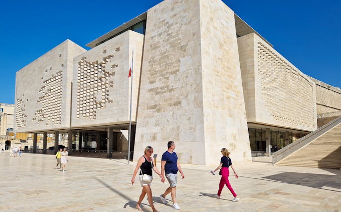 Parliament House in Valletta with tourists walking nearby.