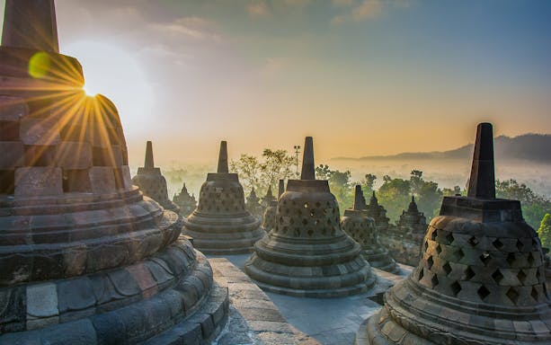 Borobudur temple stupas at sunrise during guided tour in Java, Indonesia.