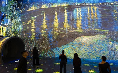 Visitors viewing Van Gogh's "Starry Night Over the Rhône" at Dutch Masters Exhibition, Fabrique des Lumières.