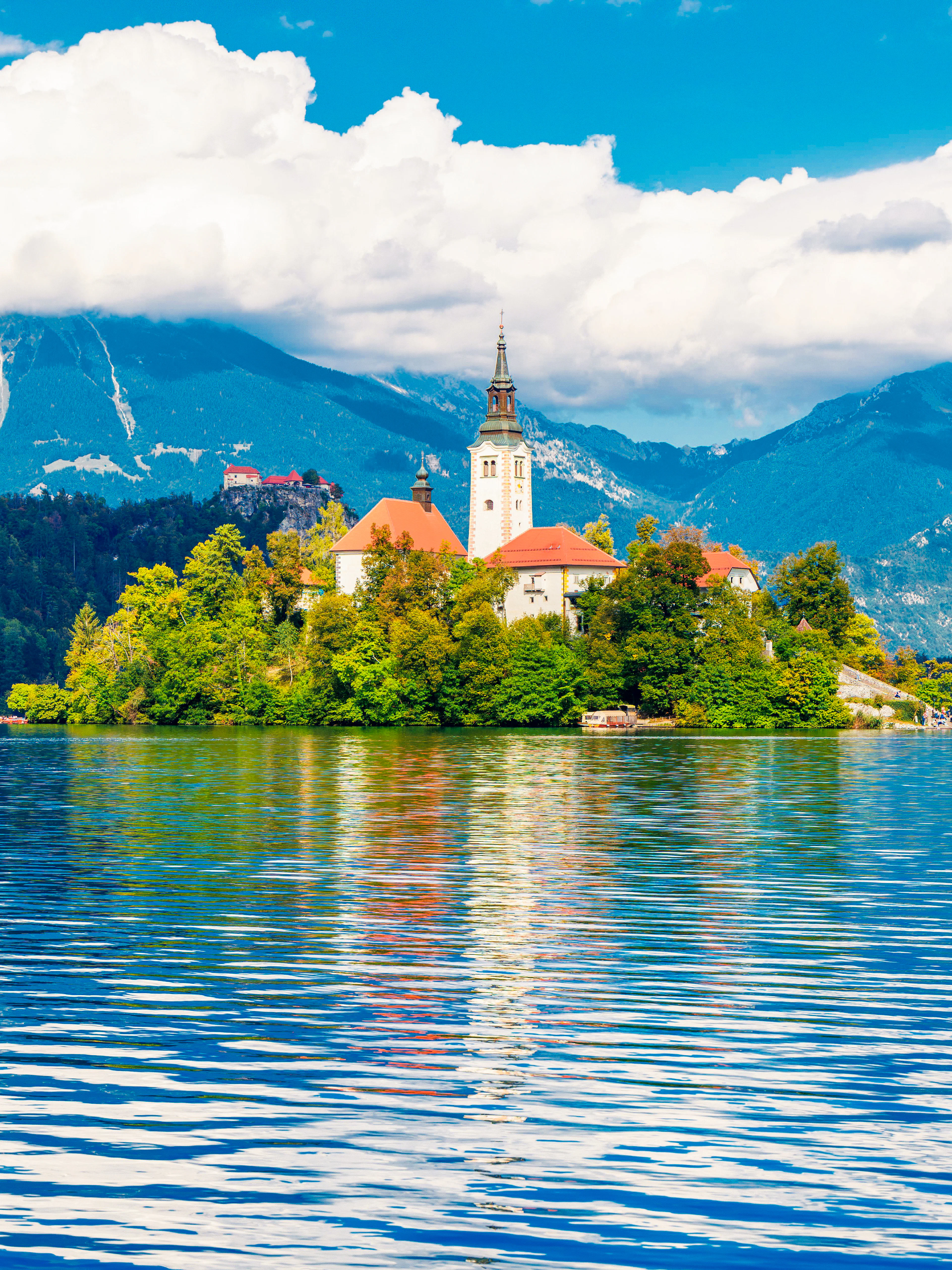 Church on Bled Island with mountains and lake in Slovenia.