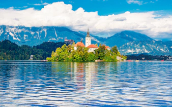 Church on Bled Island with mountains and lake in Slovenia.