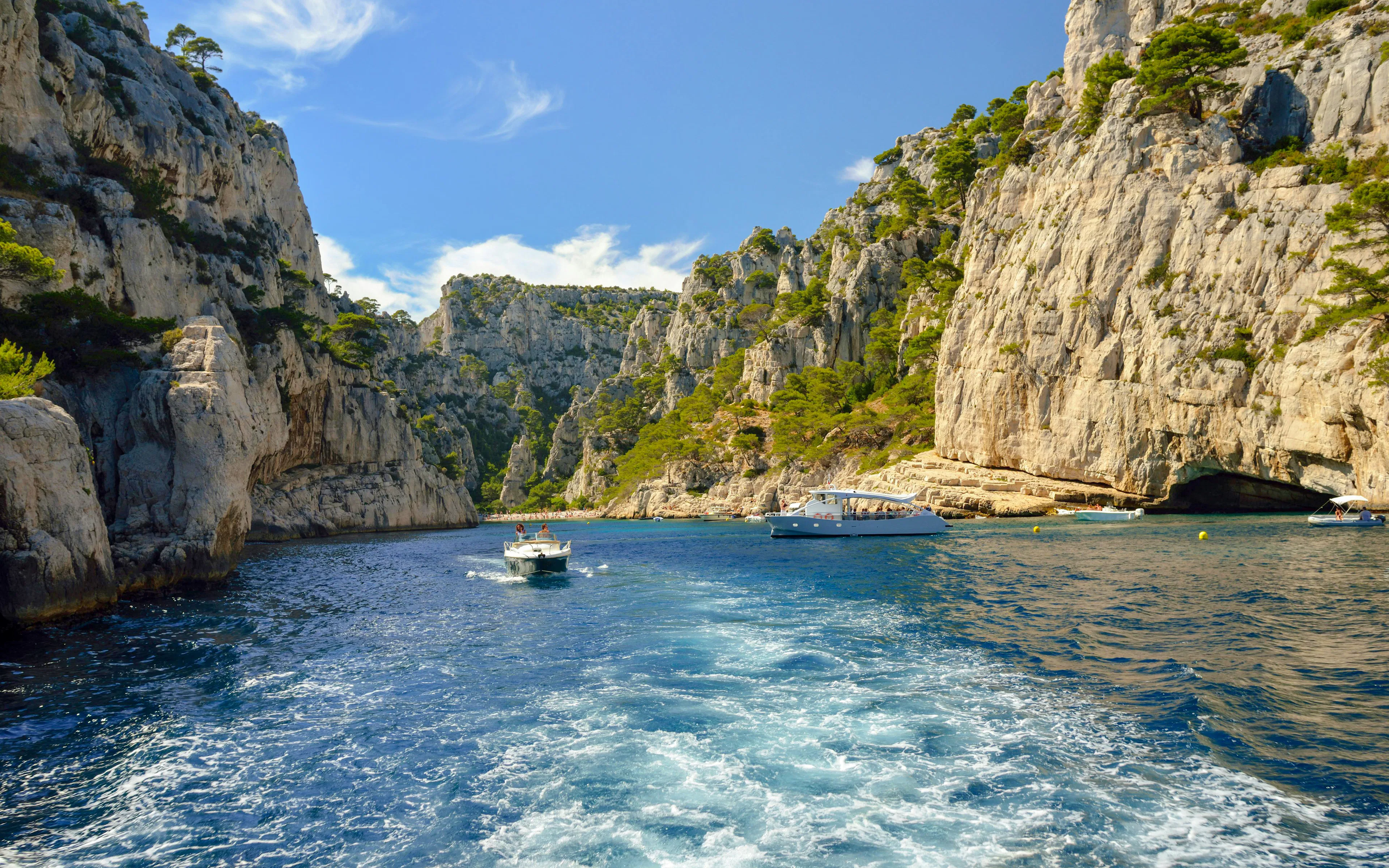 Excursion boats navigating through the cliffs of Calanques de Cassis, France.