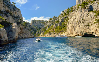 Excursion boats navigating through the cliffs of Calanques de Cassis, France.