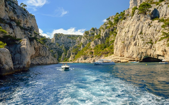 Excursion boats navigating through the cliffs of Calanques de Cassis, France.