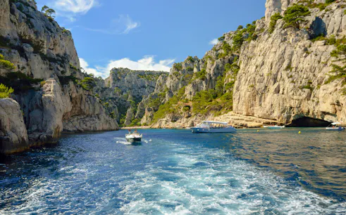 Excursion boats navigating through the cliffs of Calanques de Cassis, France.