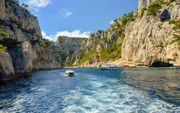 Excursion boats navigating through the cliffs of Calanques de Cassis, France.