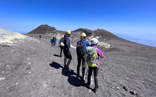 Hikers with helmets on Mount Etna summit during guided tour, Sicily.