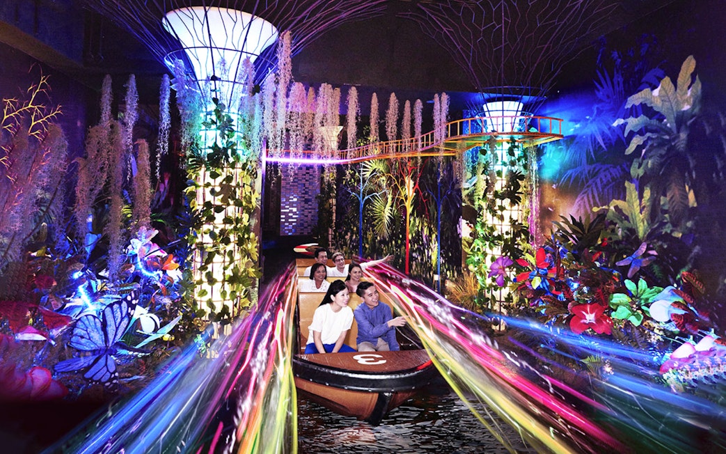 Visitors enjoying a vibrant boat ride with colorful lights and plants at Madame Tussauds Singapore.
