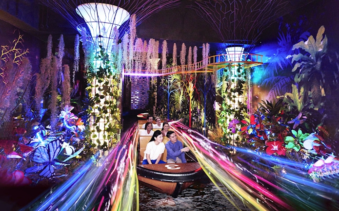 Visitors enjoying a vibrant boat ride with colorful lights and plants at Madame Tussauds Singapore.