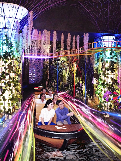 Visitors enjoying a vibrant boat ride with colorful lights and plants at Madame Tussauds Singapore.